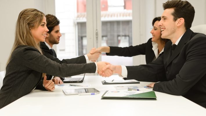 Four business people shaking hands, finishing up a meeting